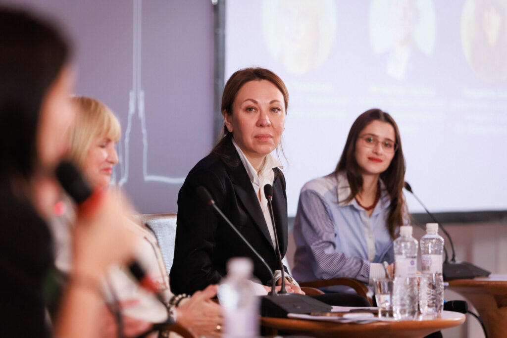 У центрі Інна Солодка, вона в темному жакеті та світлій сорочці серед панелісток Конференції. Правіше - Євгенія Булана, адвокаціна менеджерка Fight For Right, у блакитній блузі, з темним волоссям.