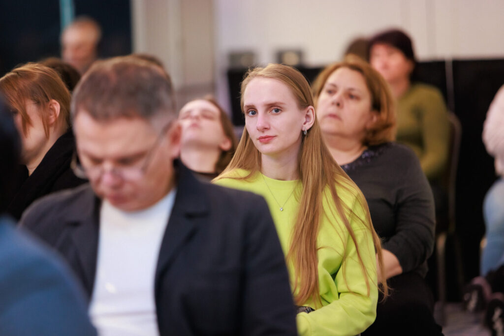 Марія Бойко, психологиня з Житомирщини, серед учасників та учасниць Конференції "Європейське майбутнє прав людей з інвалідністю". Марія у центрі фото, вона одягнена в жовтий сякравий светр. Має довге світле пряме волосся.